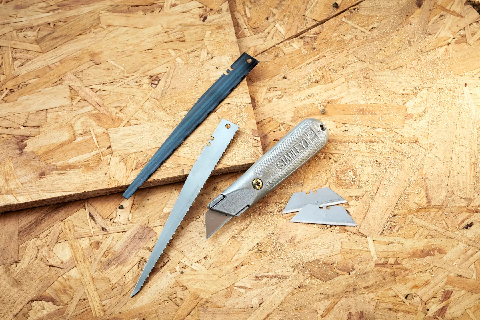 STANLEY 0-10-129 folding utility knife with blade, saw blade, cover, and spare blades on wood surface.