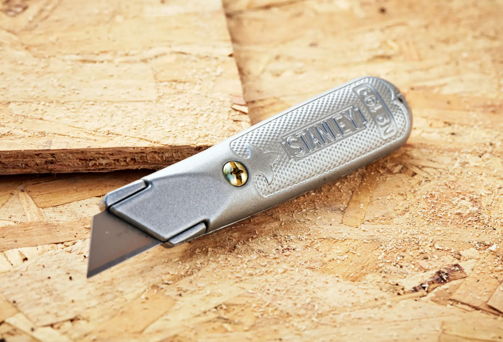 STANLEY 0-10-129 utility knife with metal handle, silver finish, shown on plywood surface.