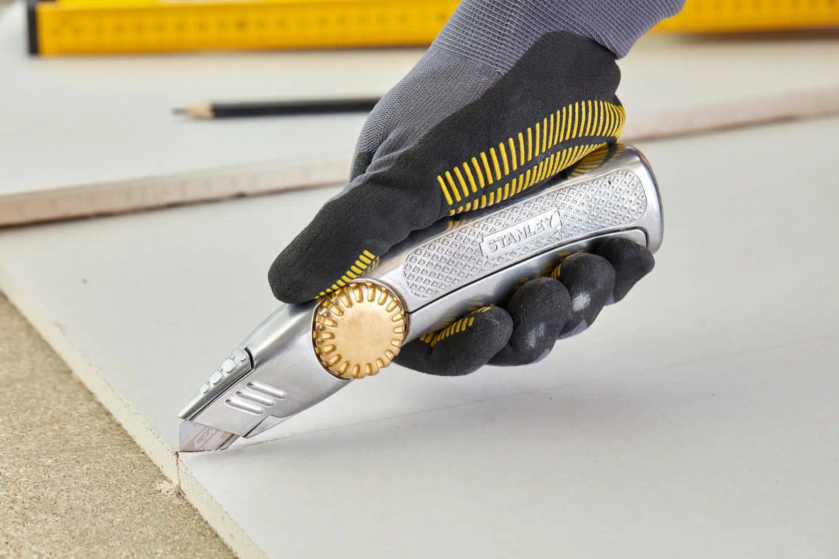 STANLEY 0-10-818 utility knife with gold wheel, cutting board, photography of gloved hand in action.