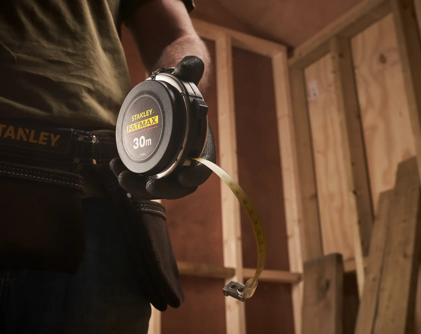 Photo of STANLEY 0-34-203 measuring tape, 30m, held by a person in a workshop.