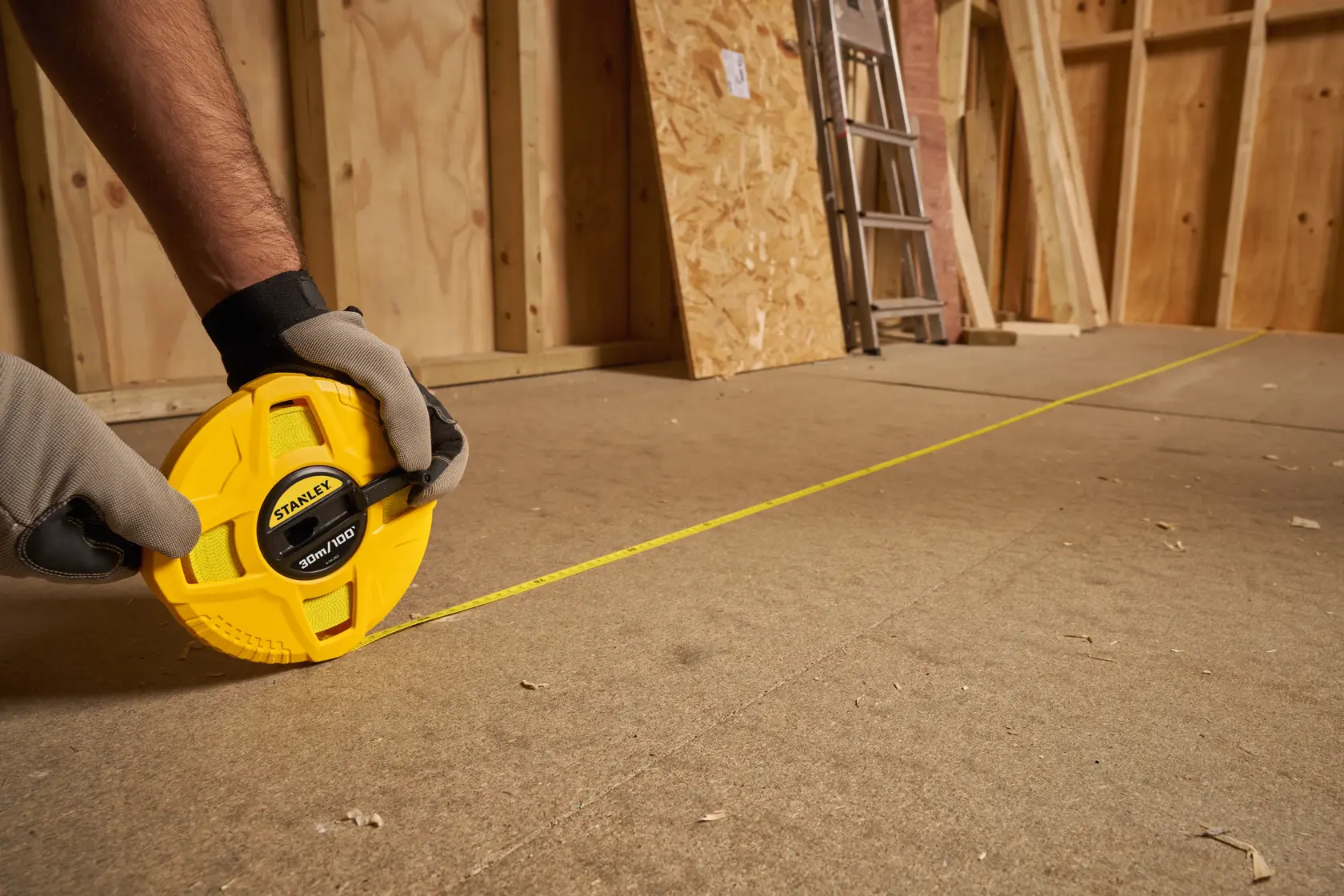 Photo of STANLEY 0-34-262 long tape measure, yellow casing, extended on construction floor.