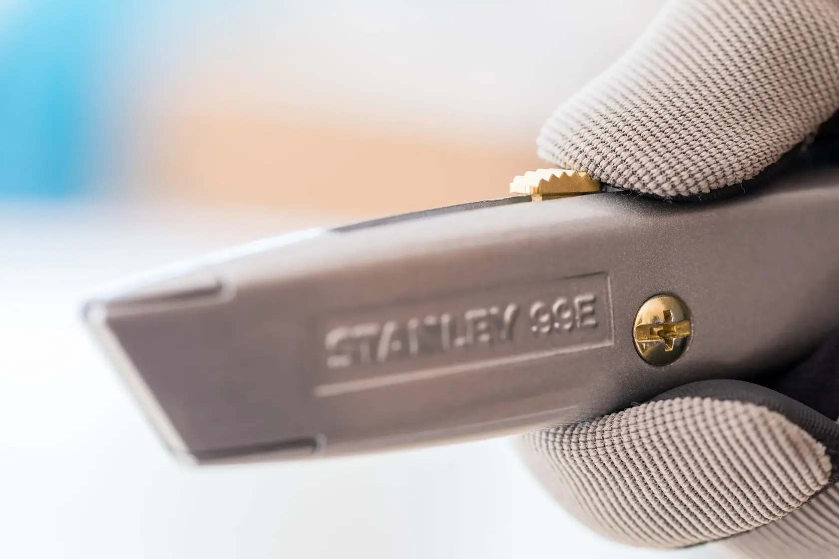 STANLEY 1-10-099 utility knife close-up held in gloved hand, showing detail of blade slider and screw.