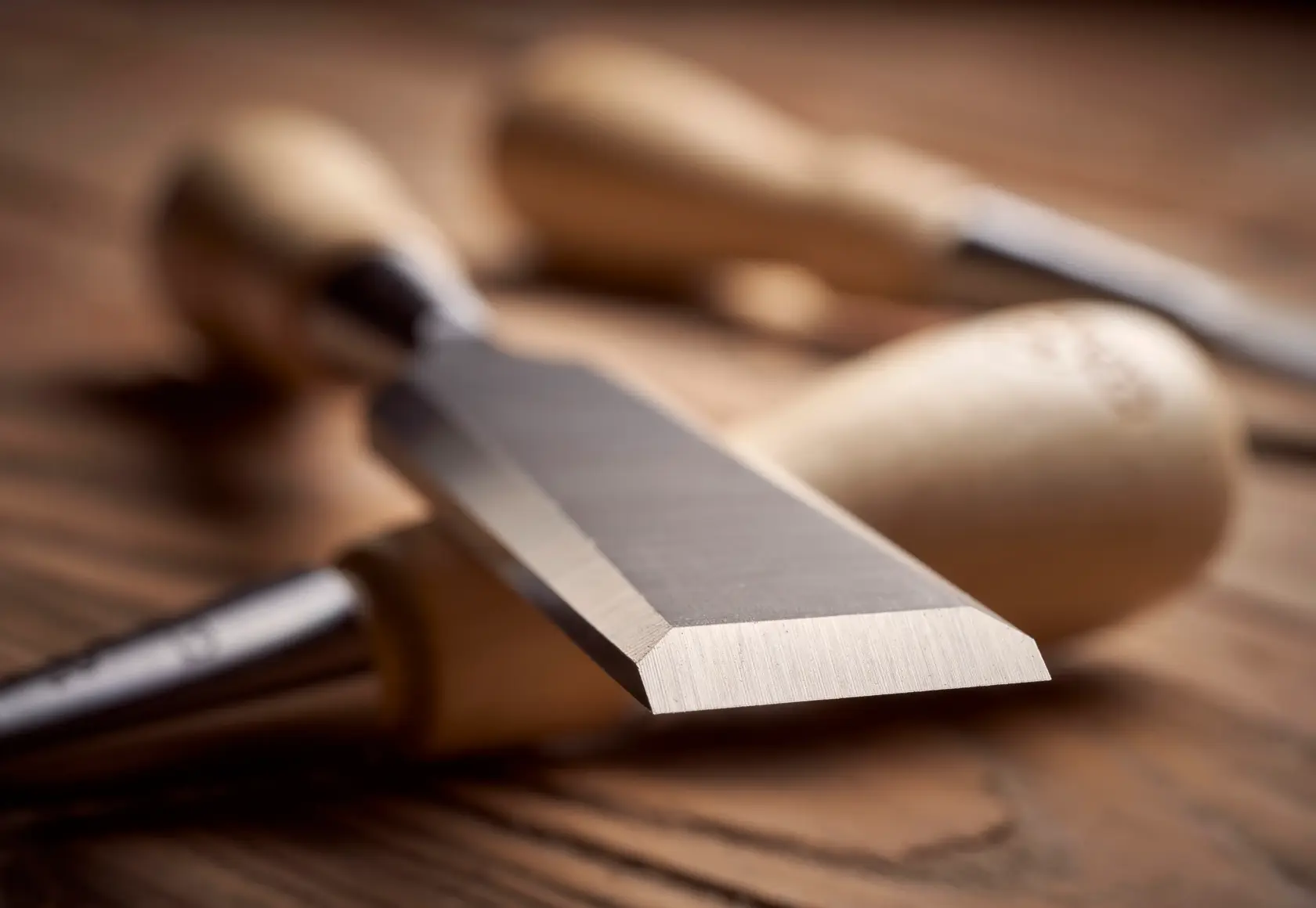 STANLEY 1-16-793 photography of wood chisel with sharp steel blade and wooden handle on wooden surface.