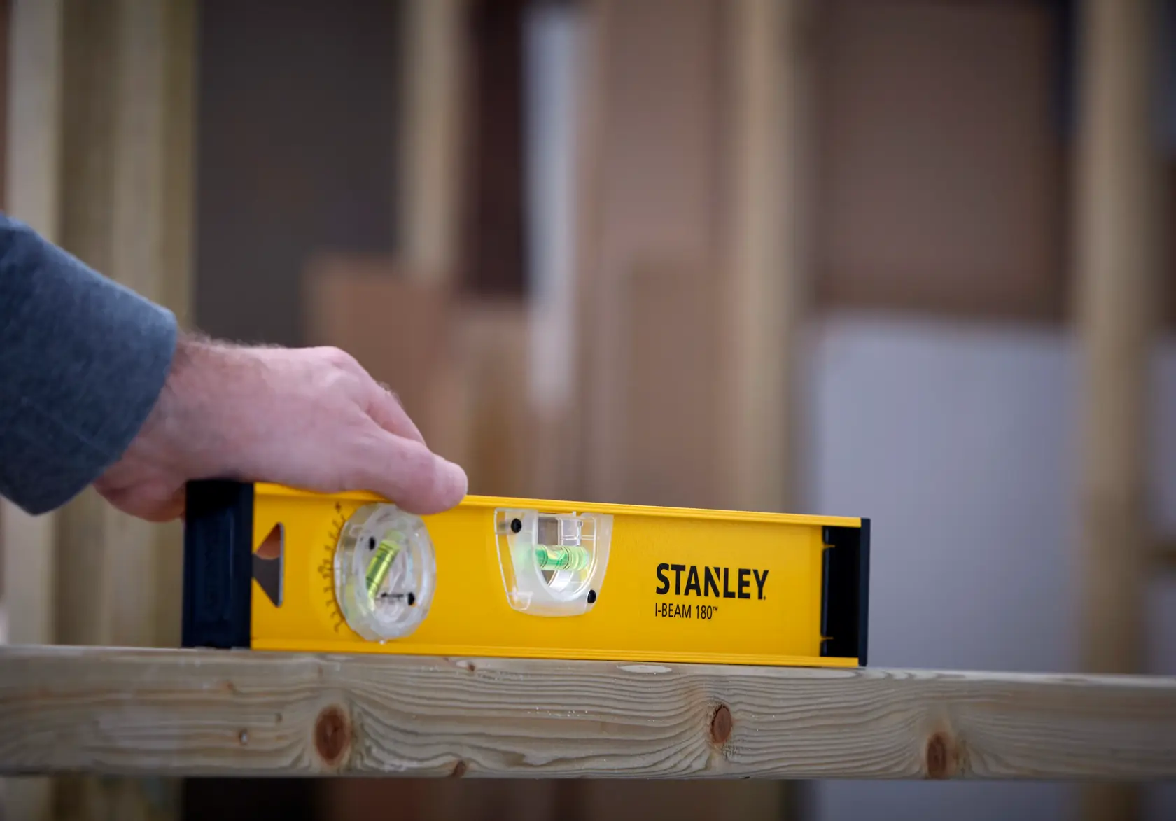 STANLEY 1-42-919 spirit level used to check level on wooden beam, close-up view.