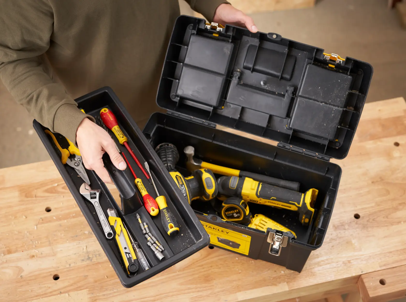 STANLEY 1-92-066 toolbox photography featuring assorted hand and power tools on a wooden table, top angle.