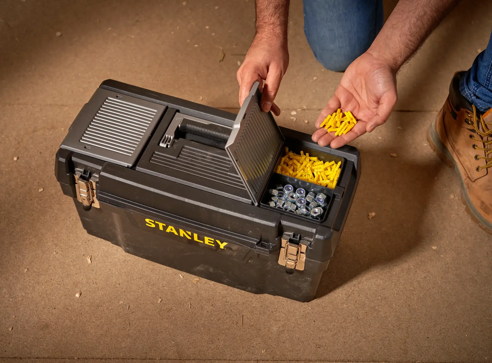 STANLEY 1-94-858 tool box with open lid, showing yellow wall plugs and metal fasteners, top angle.