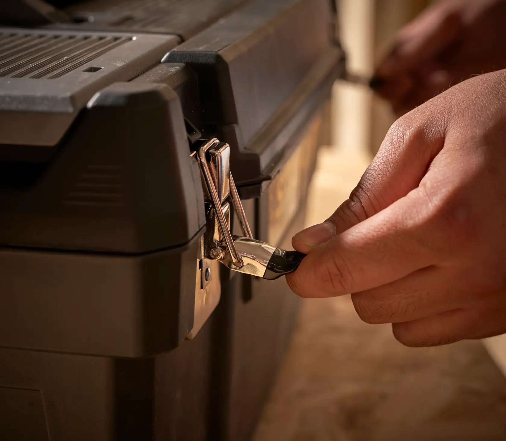 STANLEY 1-94-858 toolbox close-up with hand unlocking metal latch.
