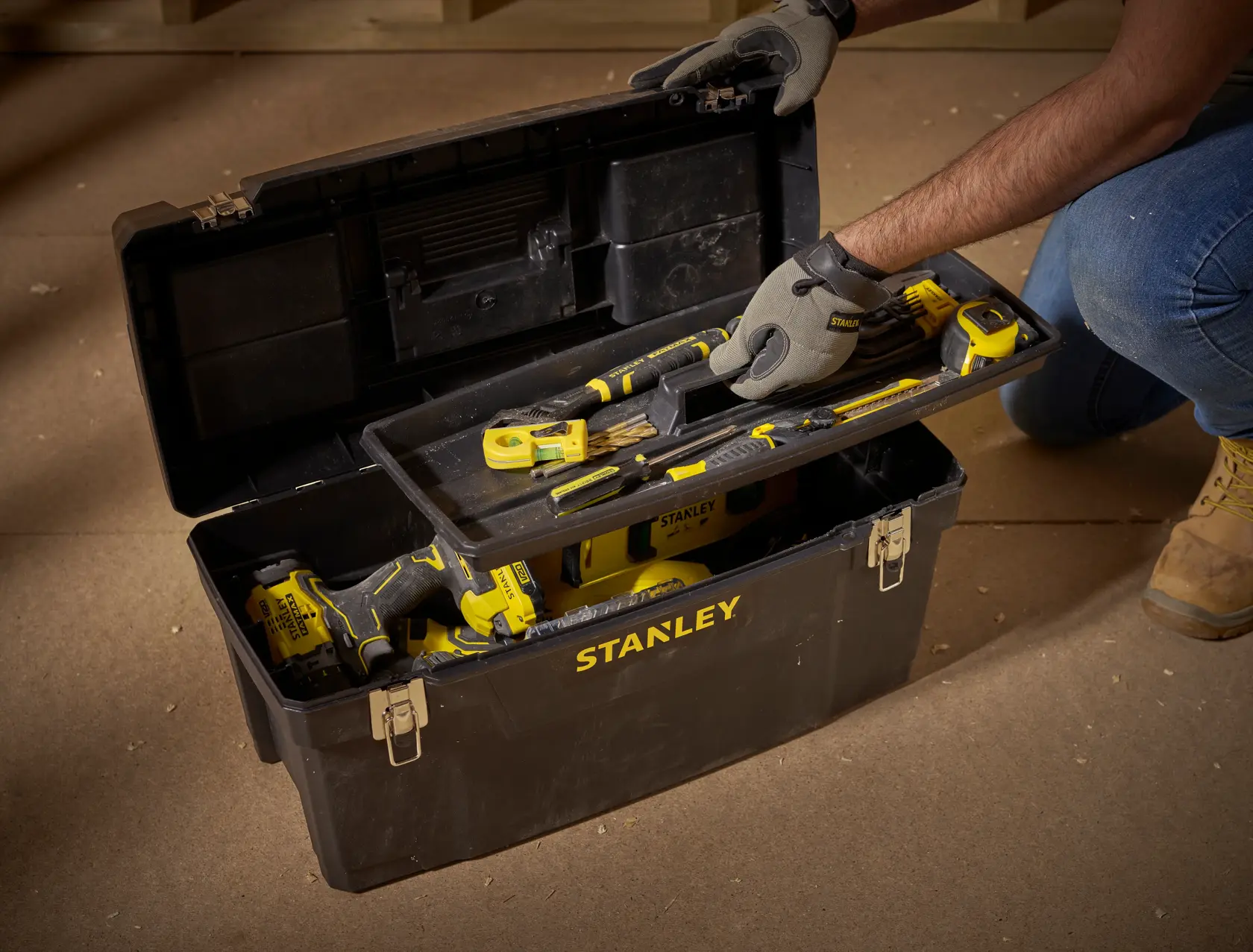 STANLEY 1-94-859 photography of black tool box with yellow tools on workshop floor, lid open, angled view.