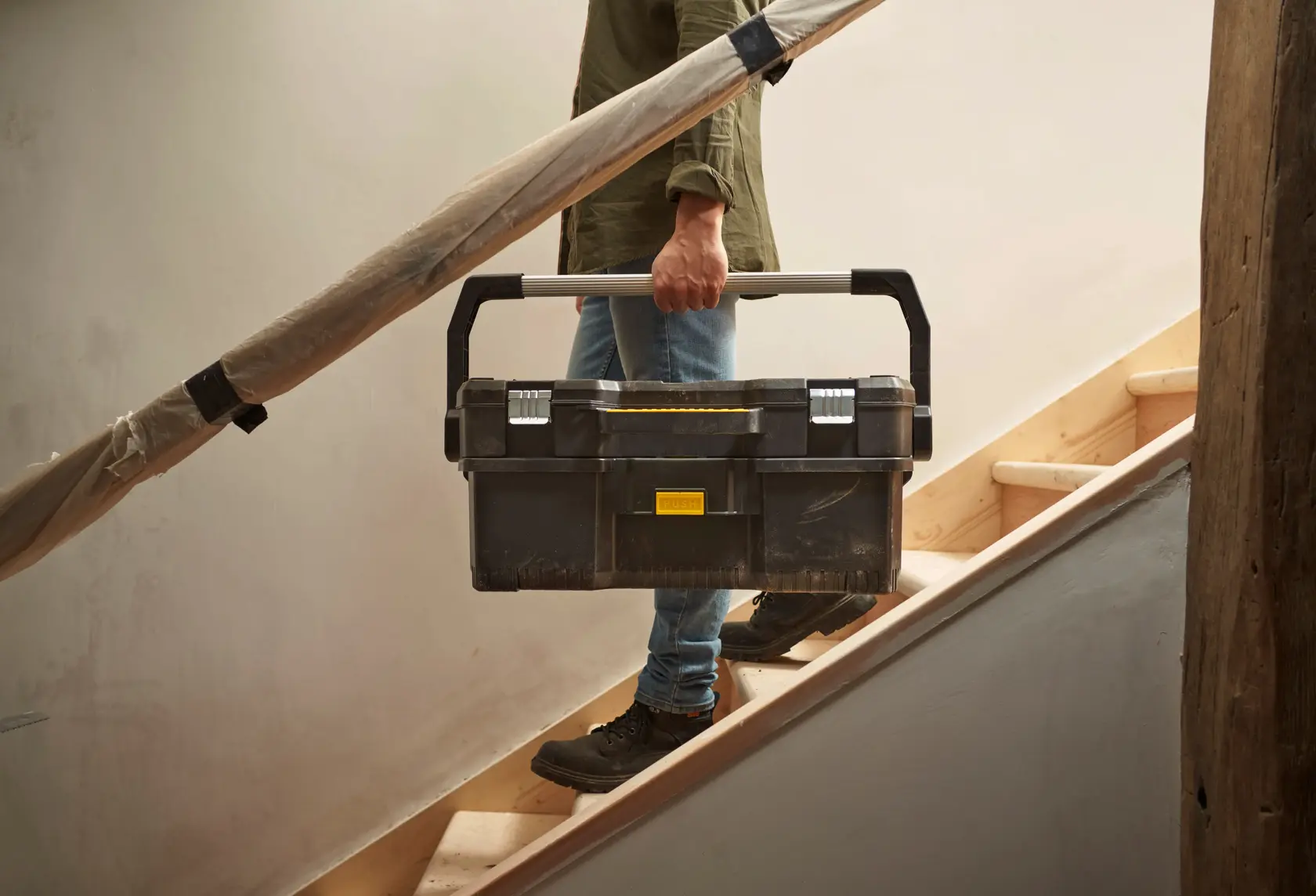 STANLEY 1-97-506 tool box being carried on stairs, black plastic case with metal handle and clasps.