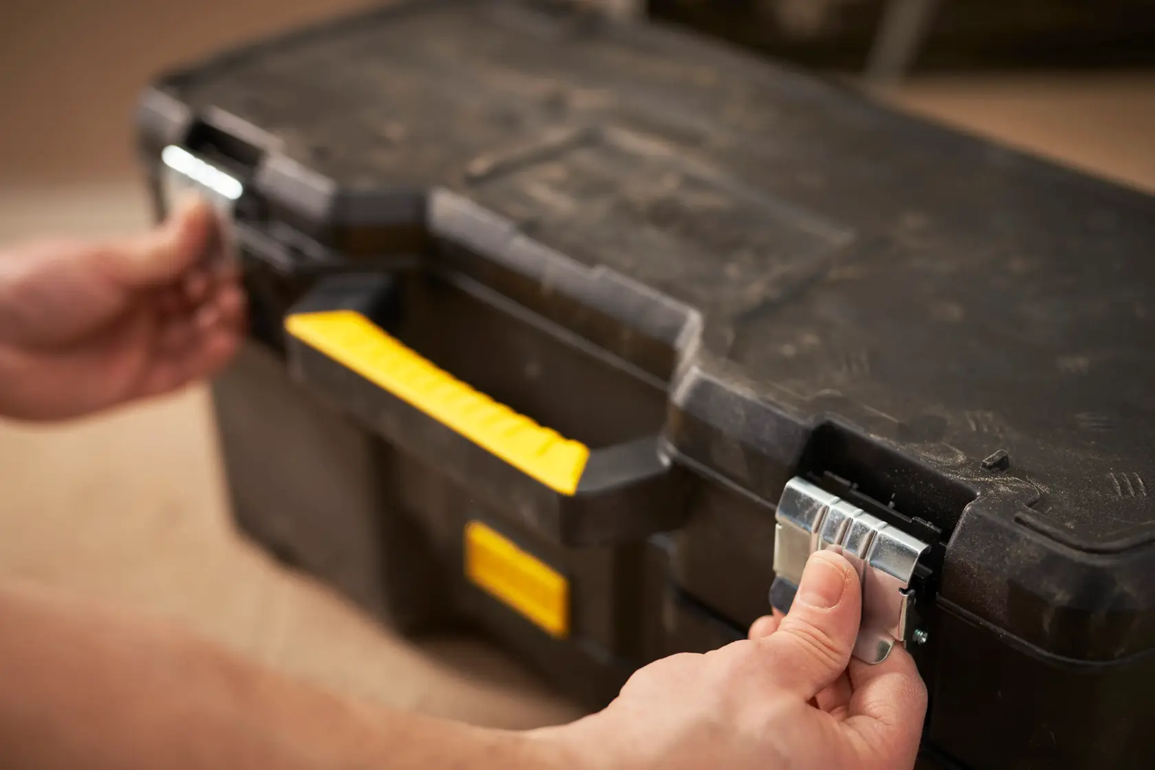 STANLEY 1-97-506 tool box with yellow handle and metal latches, hands opening front view.