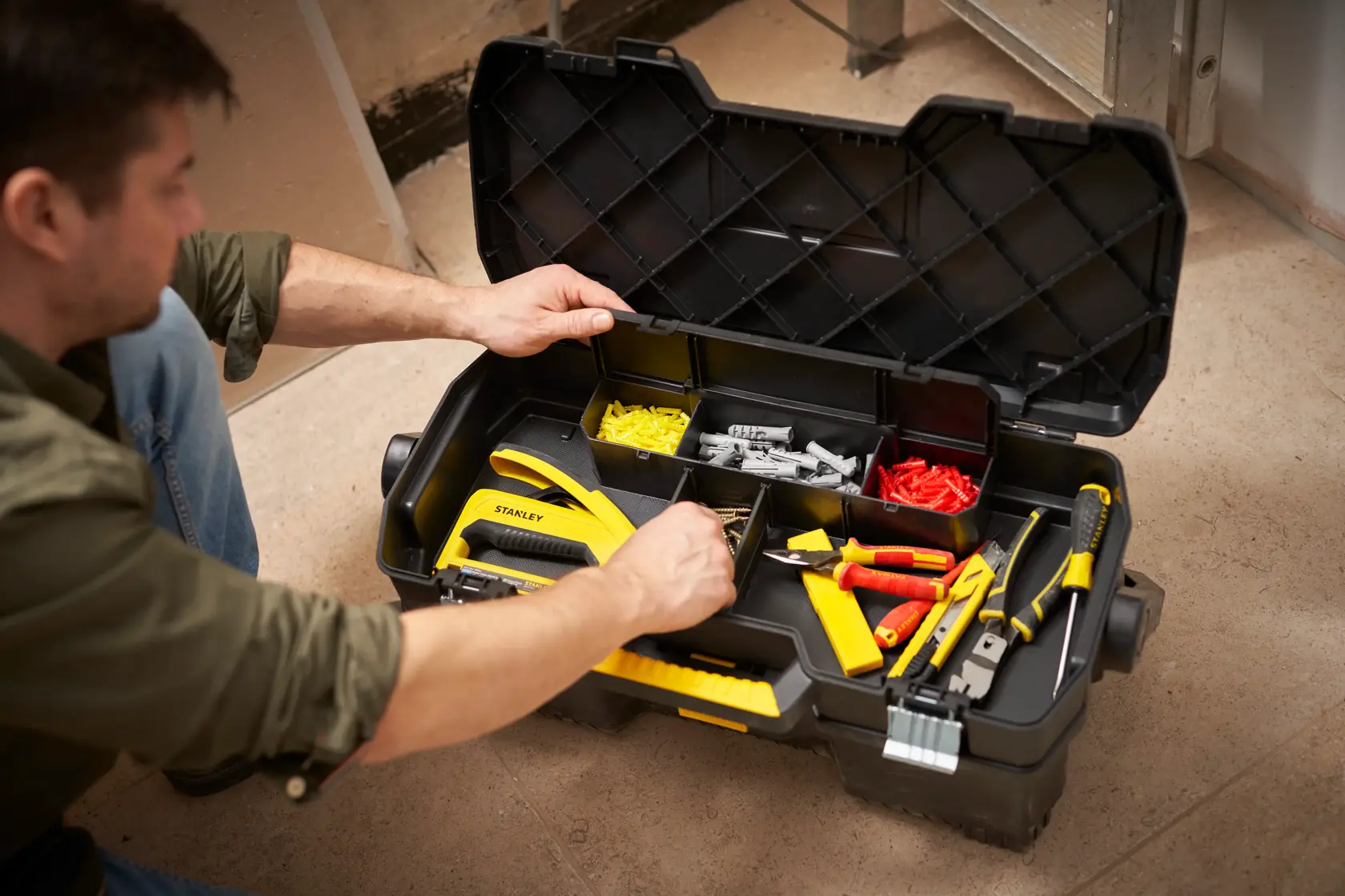 Stanley 1-97-506 tool box with organized tools and accessories, open, in use on a workshop floor.