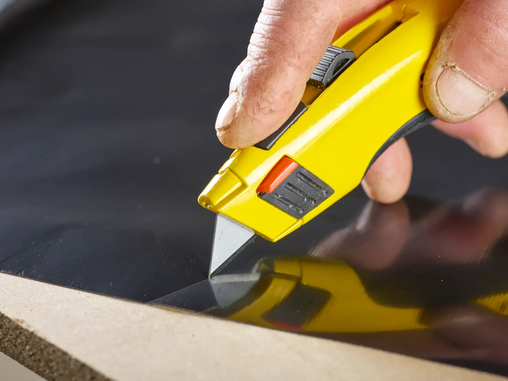 STANLEY 1-98-460 utility knife cutting black material, close-up showing yellow handle and blade.
