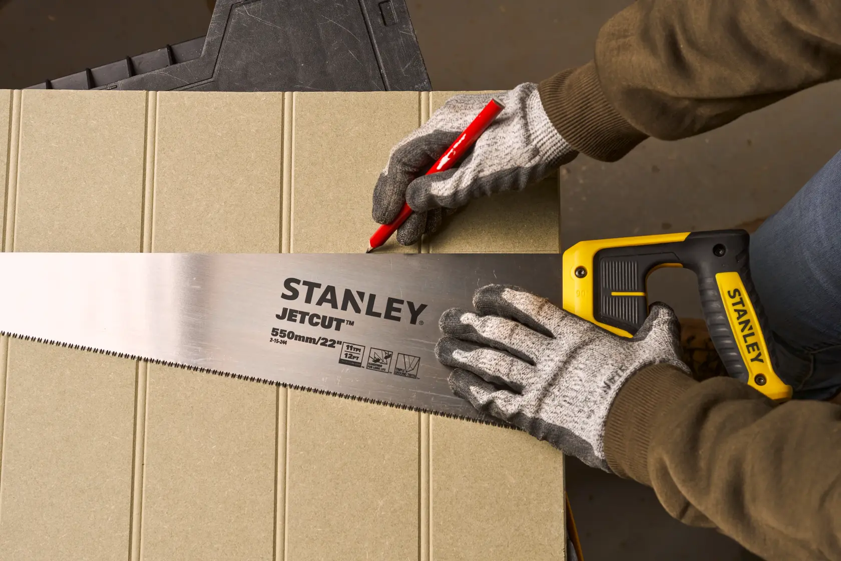 Photo of STANLEY 2-15-244 handsaw with yellow handle and JETCUT blade, used to mark a cut line on wood.