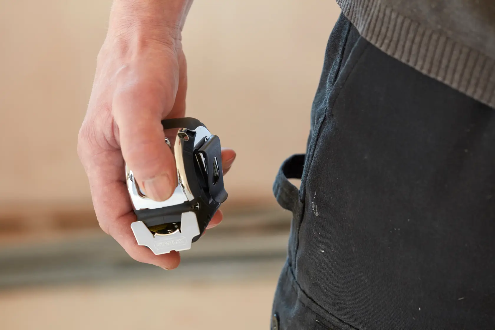 Stanley 5-33-886 tape measure held in hand close-up, black and silver finish, photography product.
