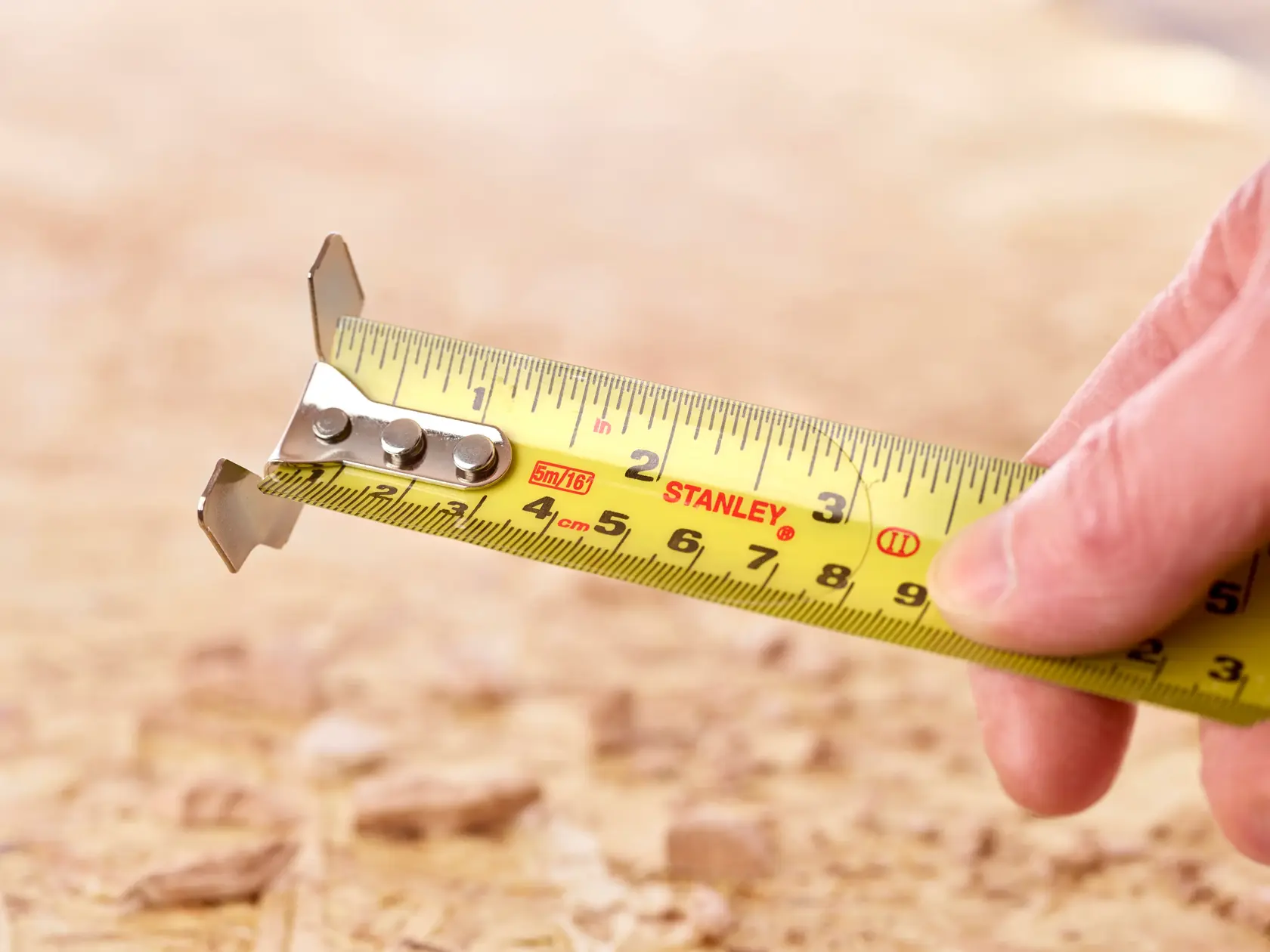 Photo of STANLEY 5-33-886 tape measure extended, with yellow blade and clear markings, held by a hand.