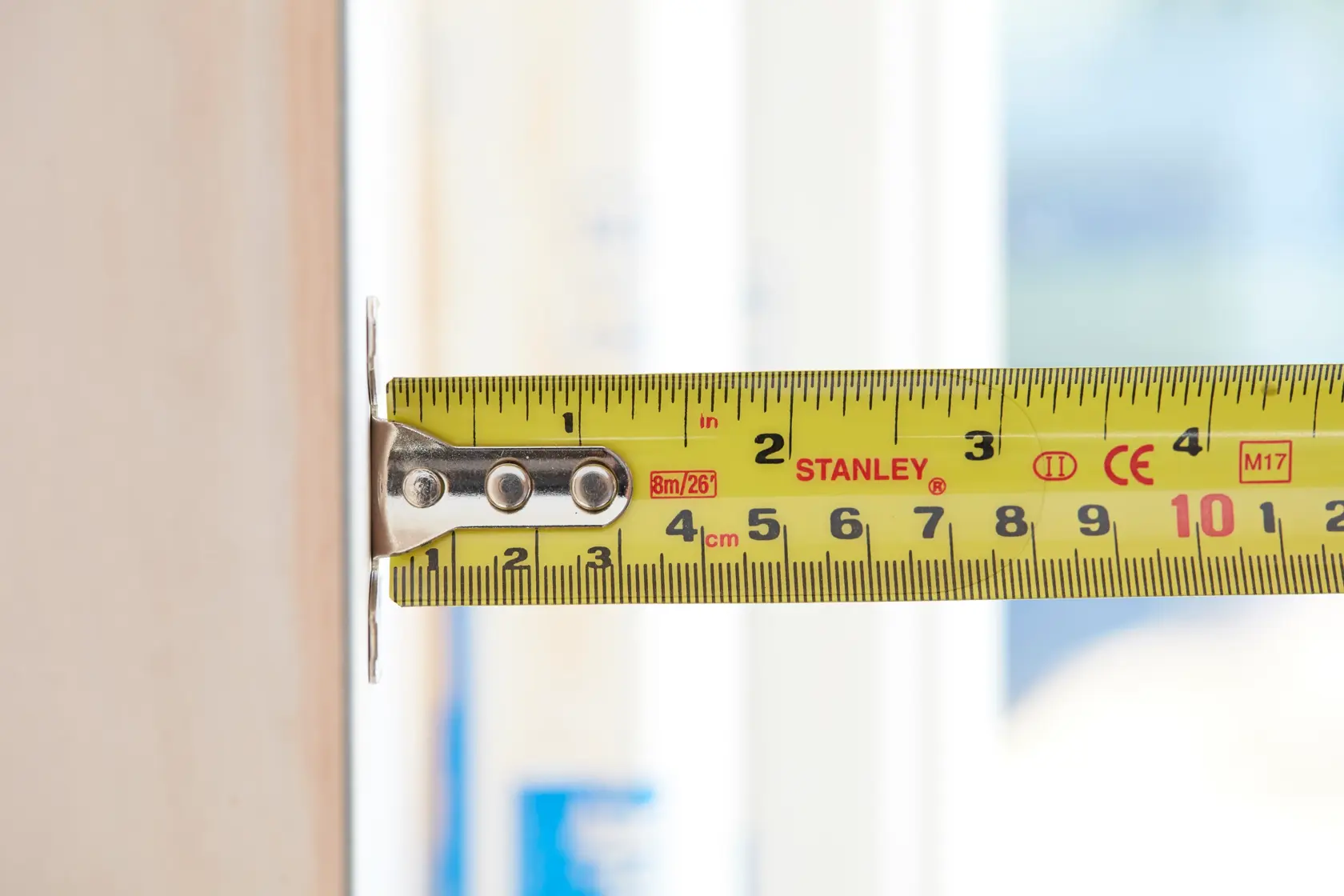 STANLEY 5-33-891 yellow tape measure in use measuring a wooden surface, close-up side view.