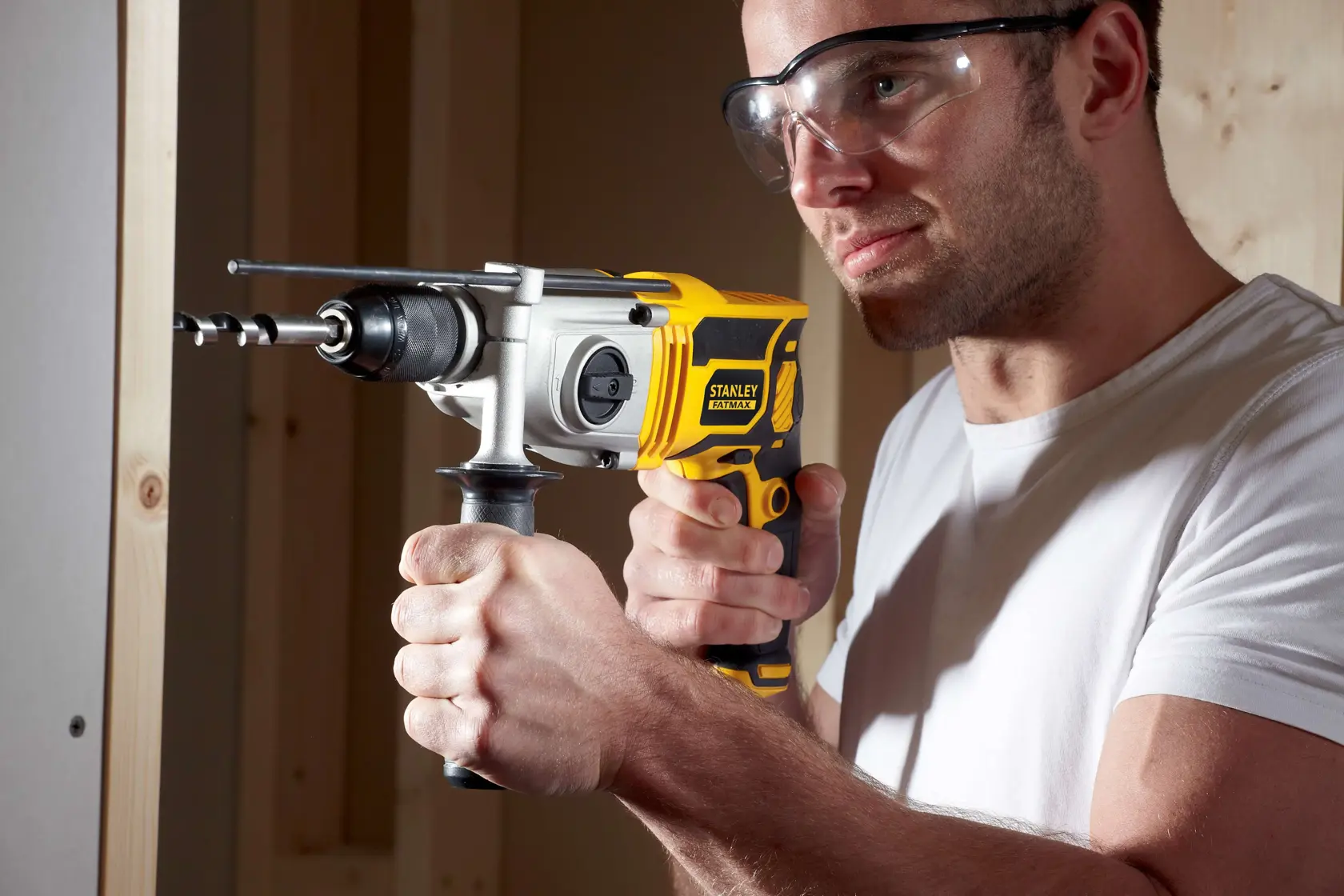 Stanley FME142K hammer drill in use, yellow and black design, being operated on a wall indoors.