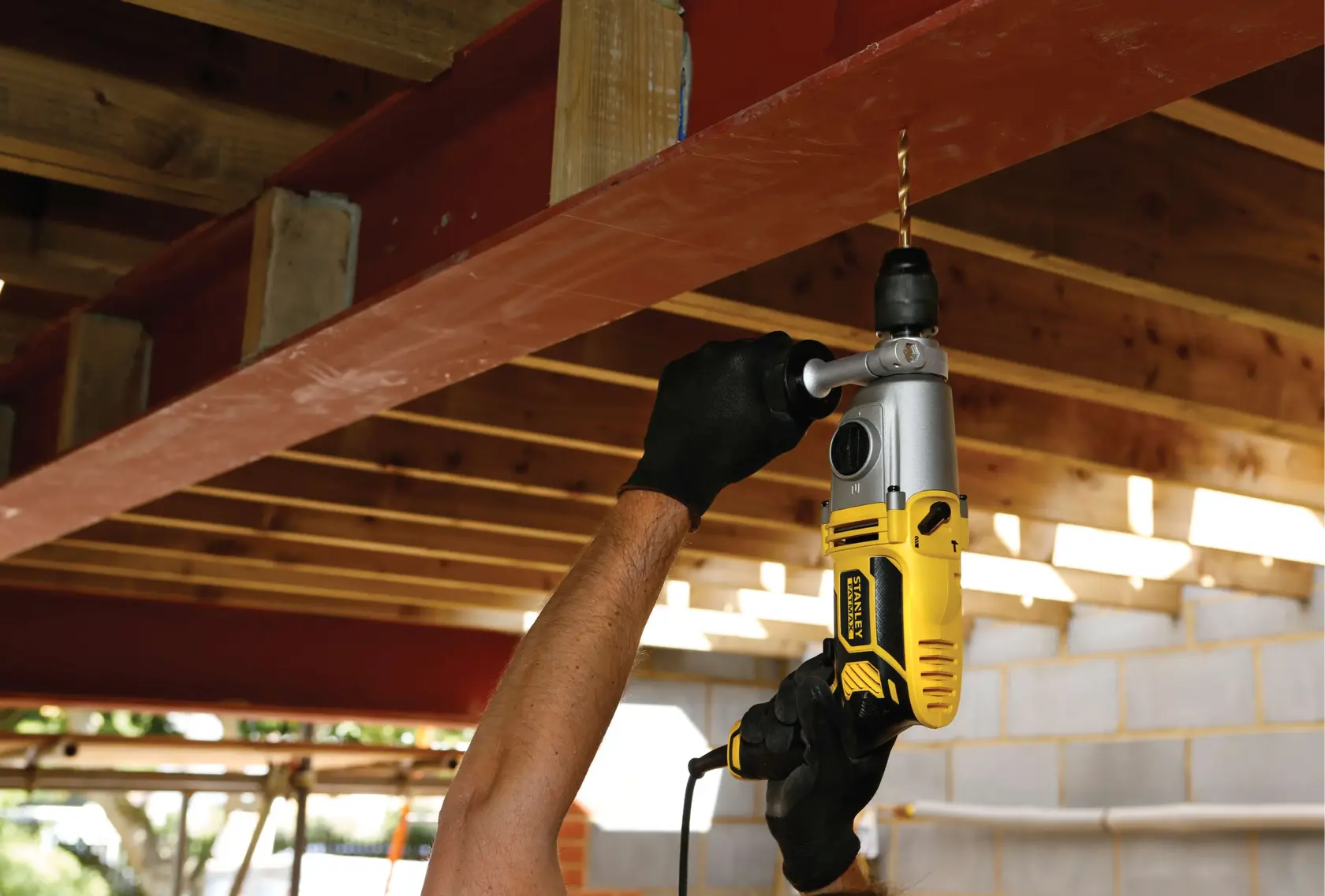 STANLEY FME142K drill in use drilling into a steel beam during construction, close-up view.