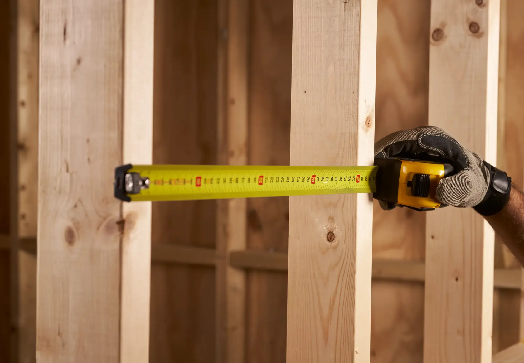 STANLEY FMHT0-33868 tape measure being used to measure wooden studs, close-up, construction setting.