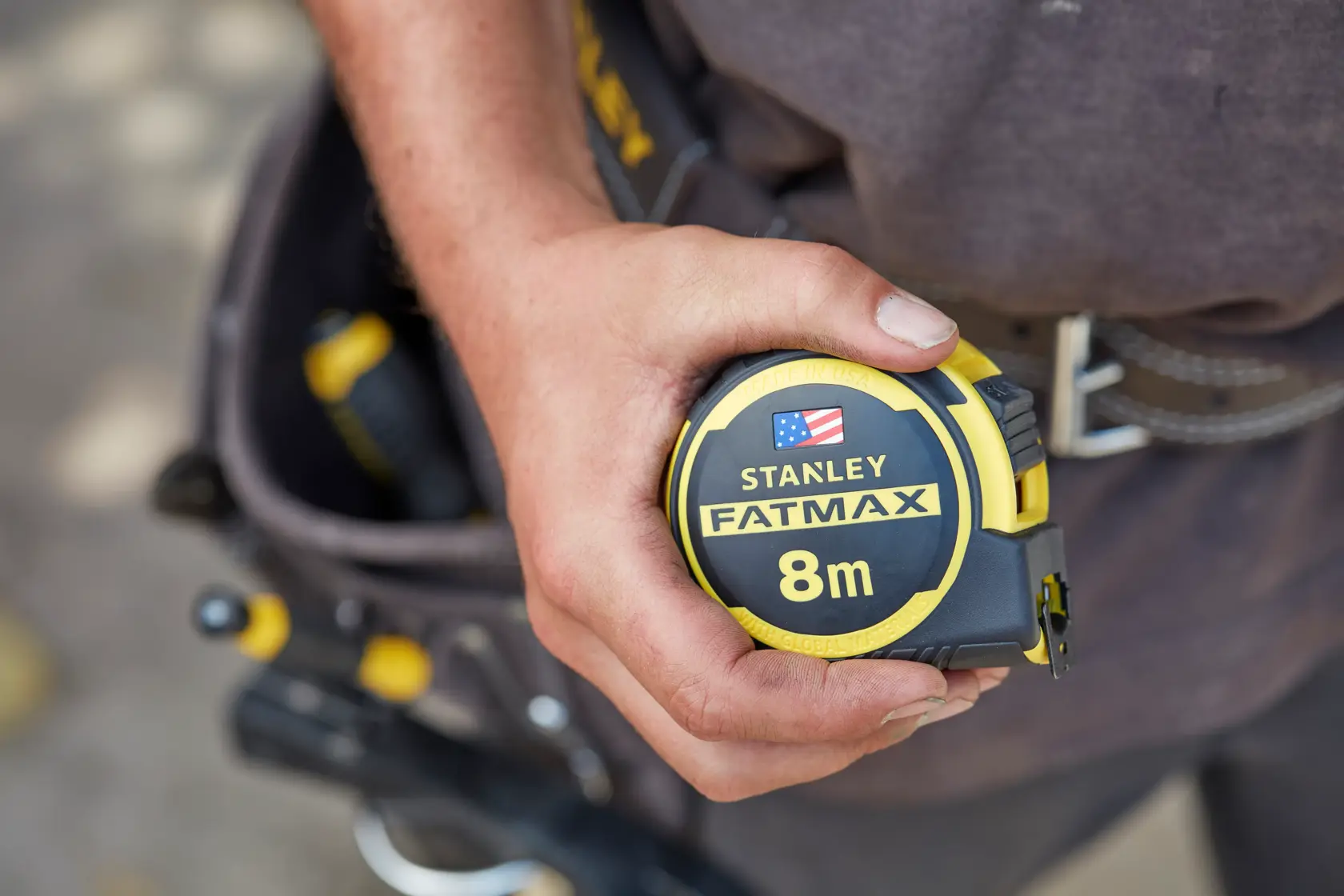 Stanley FMHT0-36327 FatMax 8m tape measure held in hand, yellow and black, close-up view.