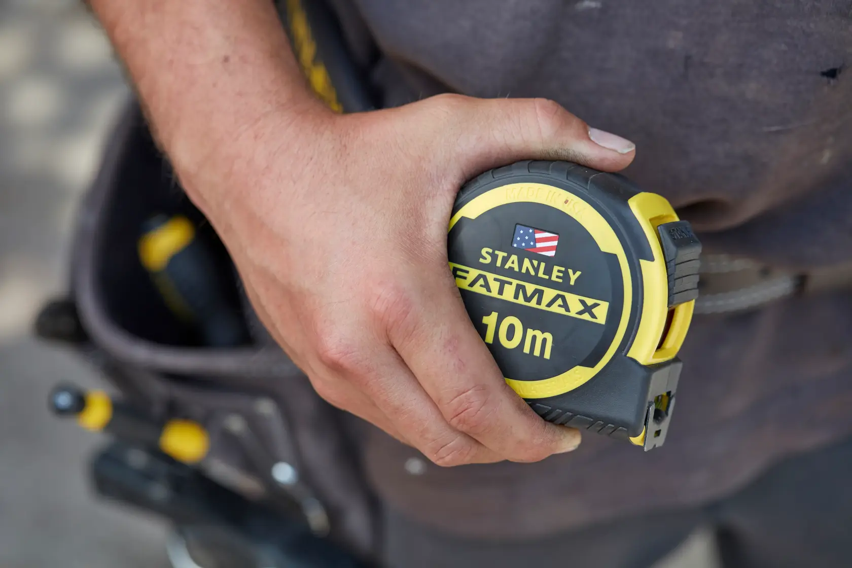 STANLEY FMHT0-36337 FATMAX 10m tape measure held in hand, close-up, yellow and black design.