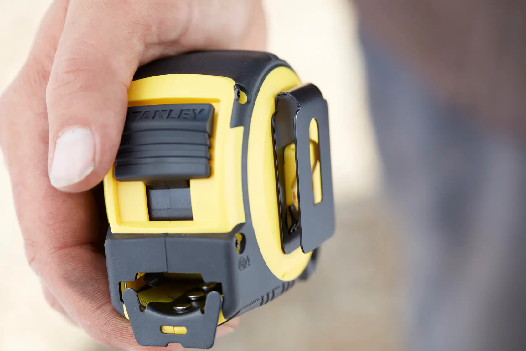 Photo of STANLEY FMHT0-36337 tape measure, yellow and black, close-up in hand.
