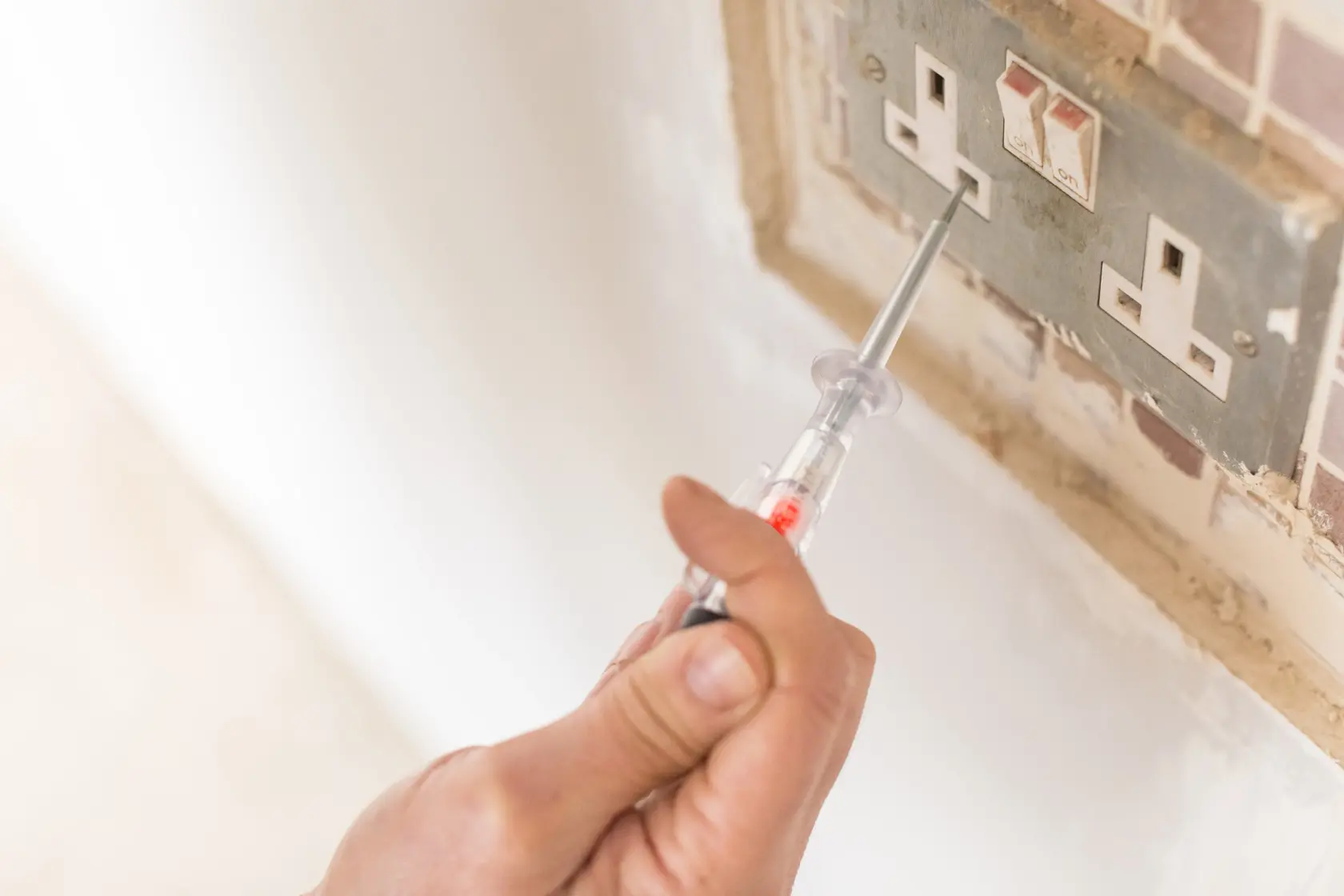 Photo of STANLEY FMHT0-64985 voltage tester used at electrical outlet, close-up hand view.