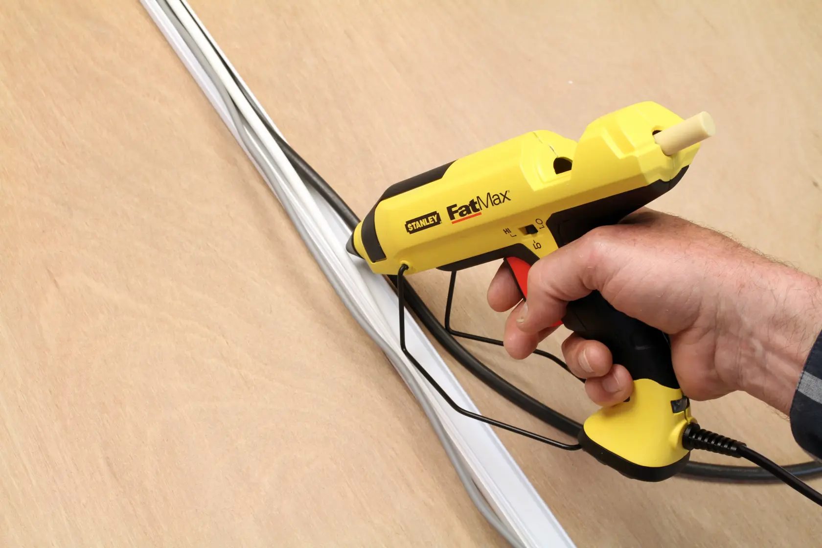 STANLEY FMHT0-70418 hot glue gun, yellow and black, hand-held, applying glue to white cables
