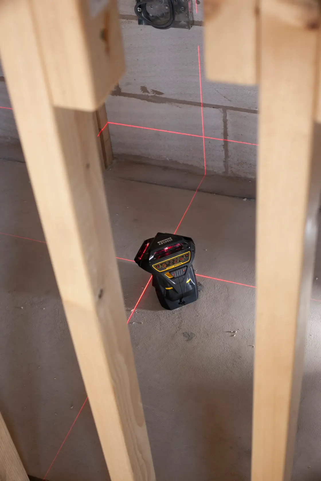 STANLEY FMHT1-77357 laser level projecting red lines in a construction site, shown from above.