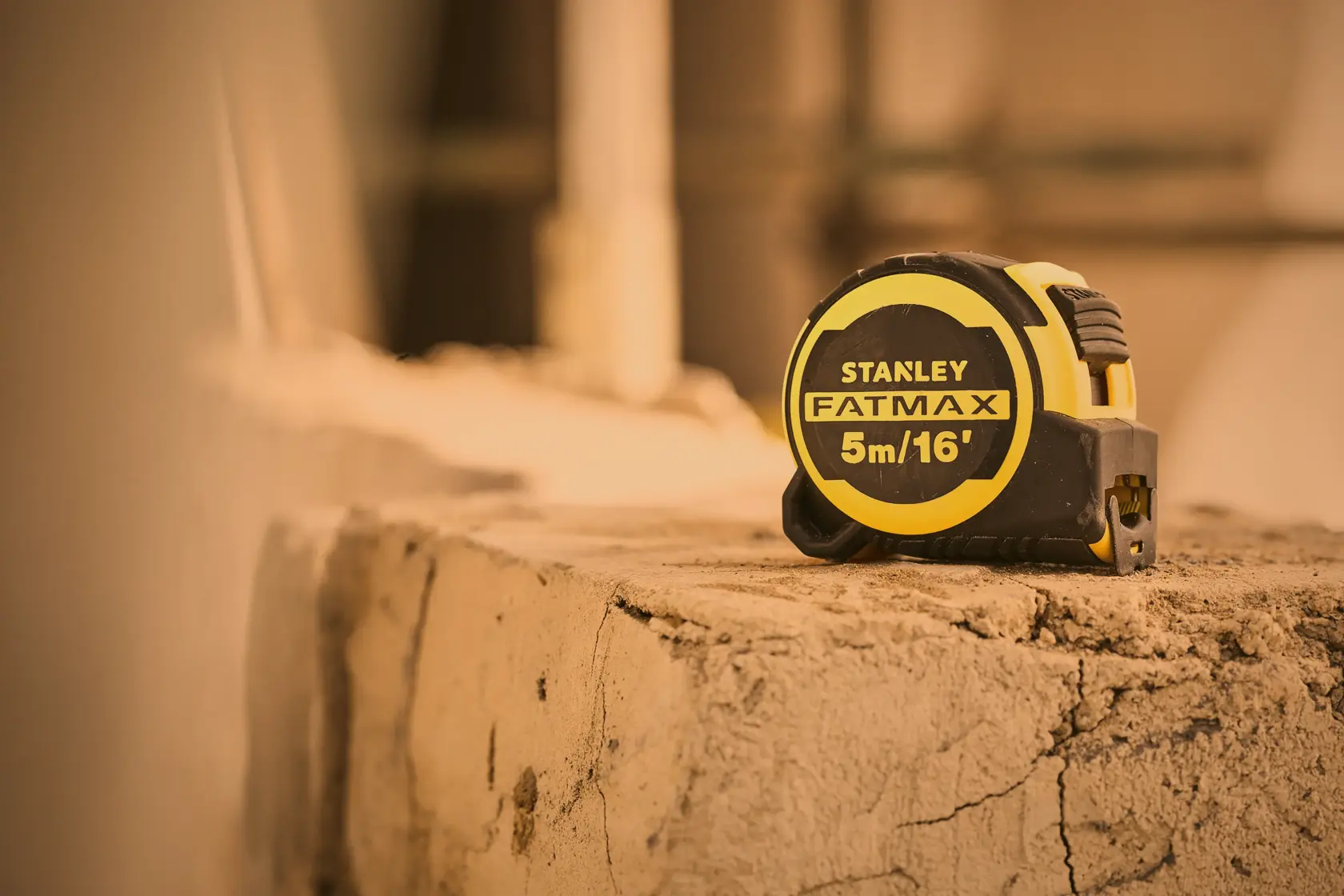 Photo of STANLEY FMHT33006-5 FATMAX tape measure 5m/16', black and yellow, on a rough concrete surface.