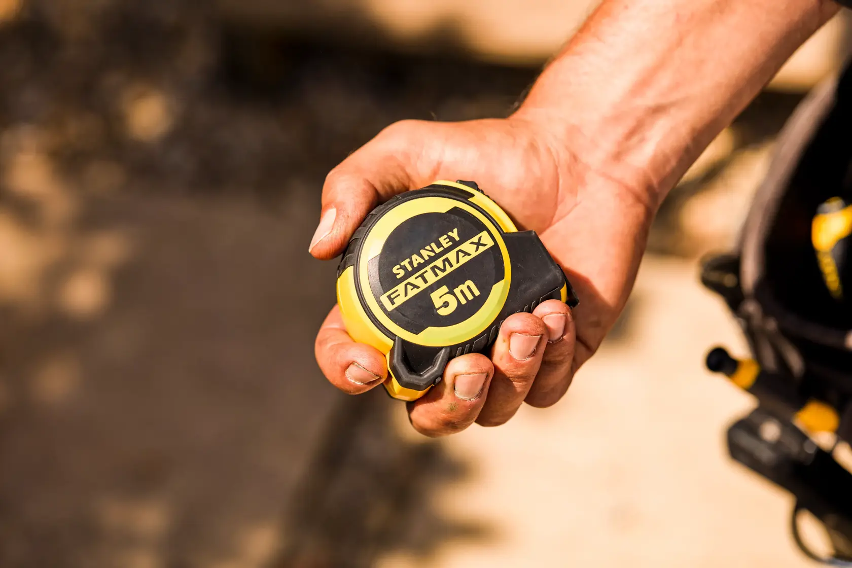Photo of STANLEY FMHT33100-0 FATMAX 5m tape measure held in a hand, yellow and black compact design.