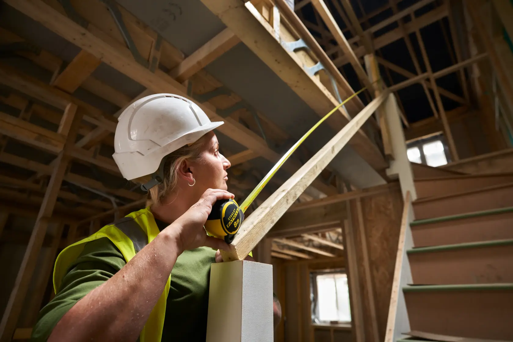Person uses STANLEY FMHT33102-0 tape measure on staircase in building under construction.