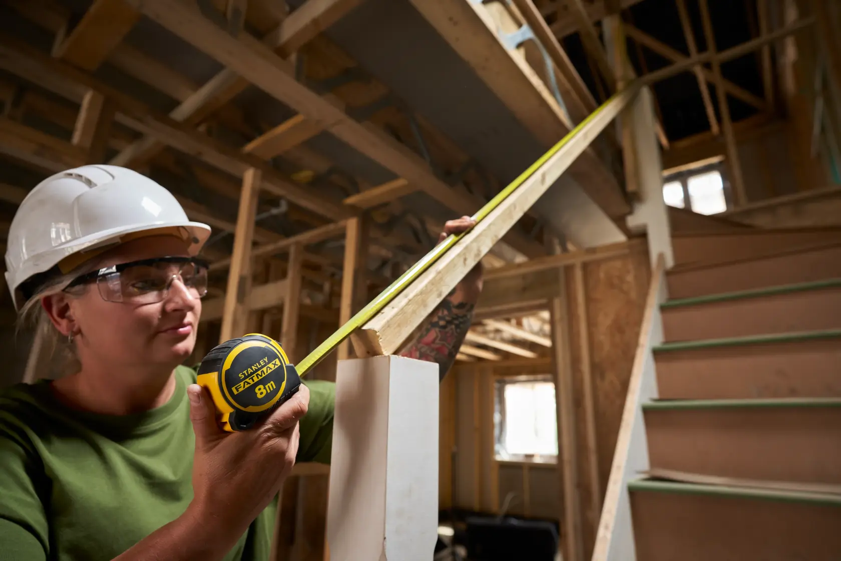 Photo of STANLEY FMHT33102-0 tape measure in use at a construction site, measuring a stair railing.