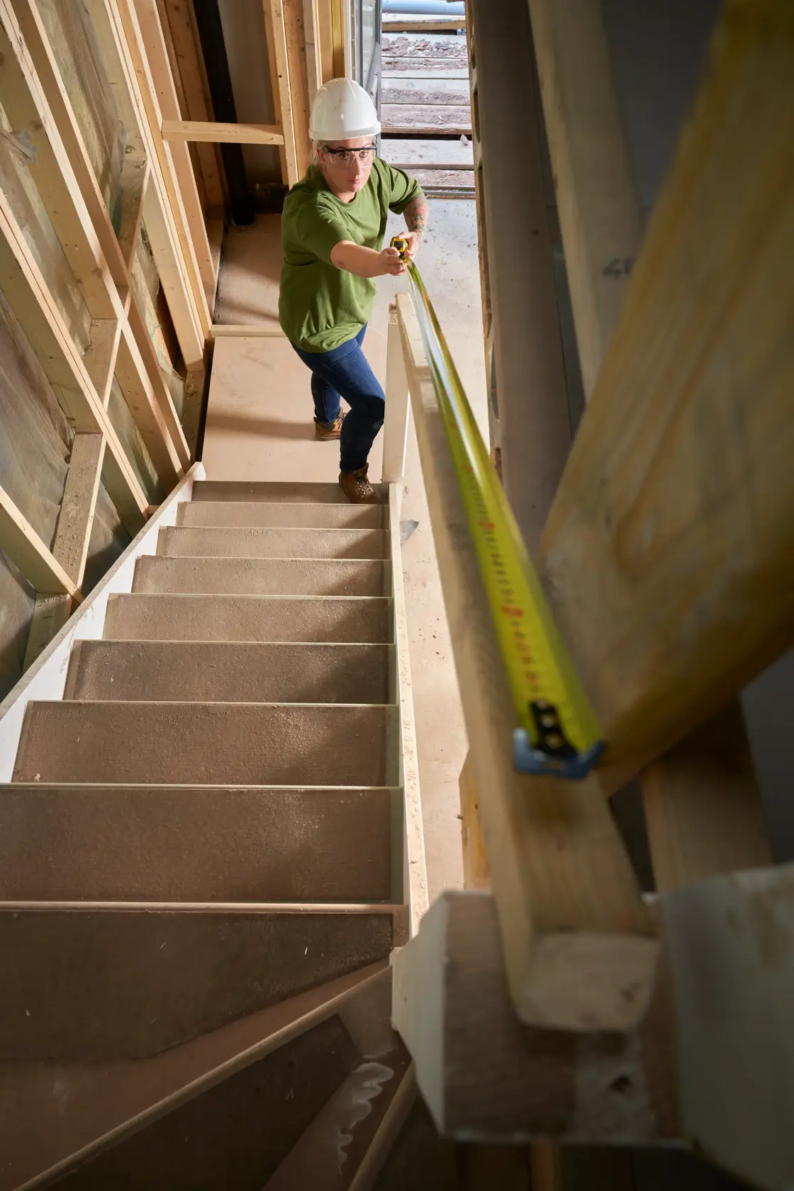 STANLEY FMHT33102-0 tape measure used for staircase measurement in construction area, angled from above.