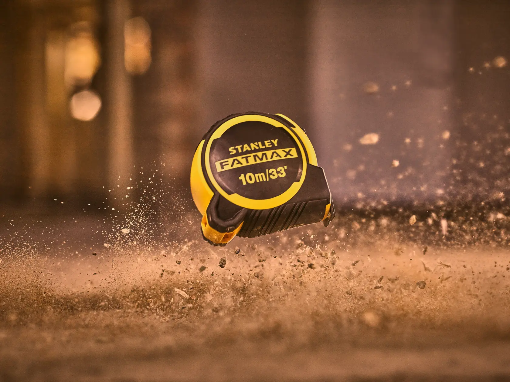 STANLEY FMHT33104-5 FATMAX tape measure, 10m/33ft, yellow and black, photographed mid-air with dust.