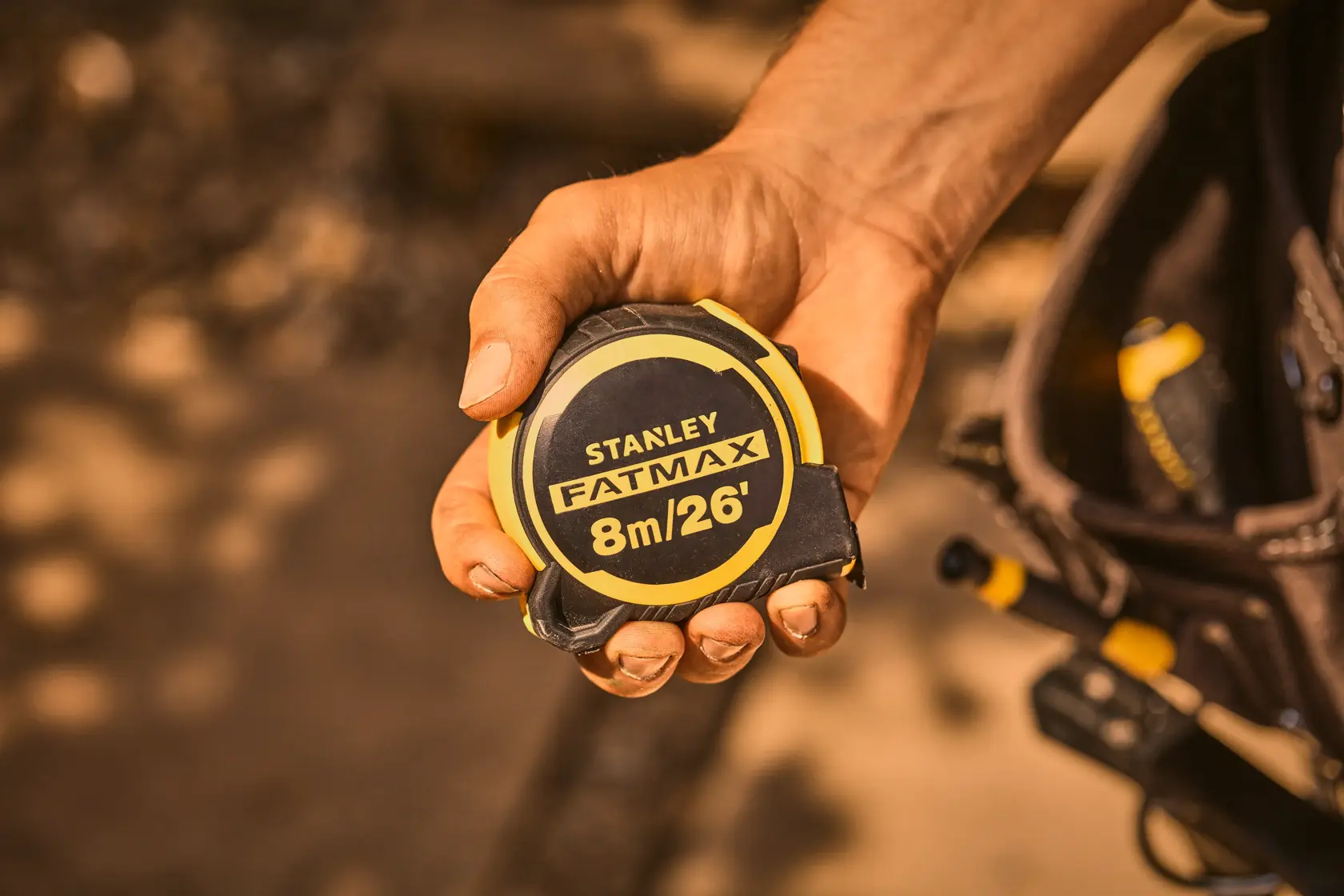 Photo of STANLEY FMHT33105-5 FATMAX 8m/26ft tape measure held in a hand, black and yellow casing.