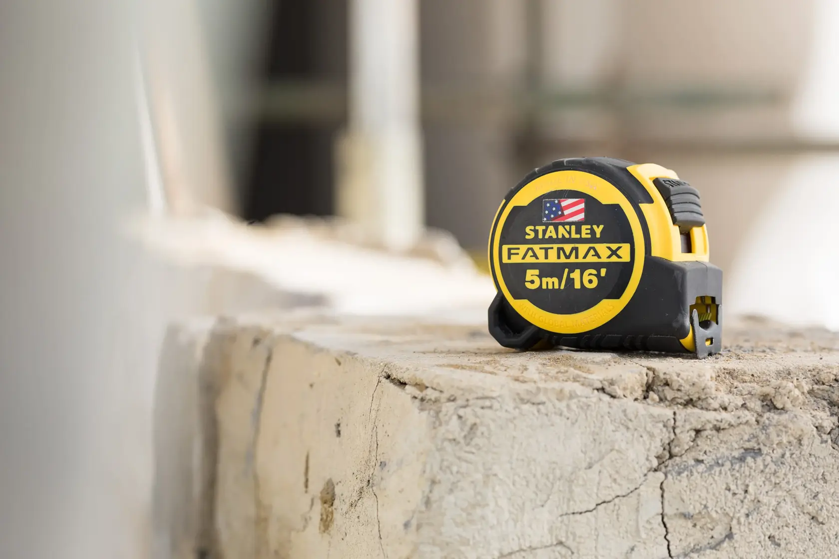 STANLEY FMHT36317-0 tape measure, FATMAX 5m/16ft, yellow and black, on rough concrete surface.