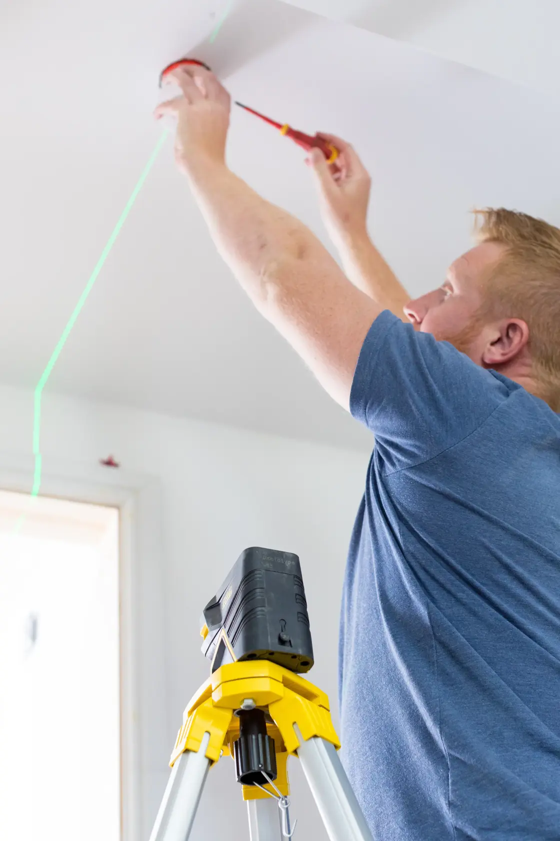 STANLEY FMHT77597-1 laser level on tripod projecting green line for ceiling installation.