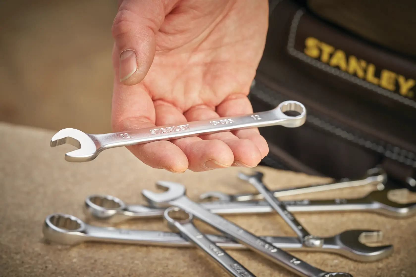 STANLEY FMMT13034-0 photography of chrome combination wrench held in hand, others on table.