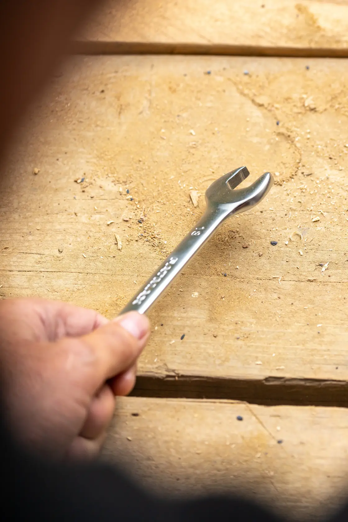 STANLEY FMMT13034-0 wrench held by hand on wooden surface, silver finish, open-end design.