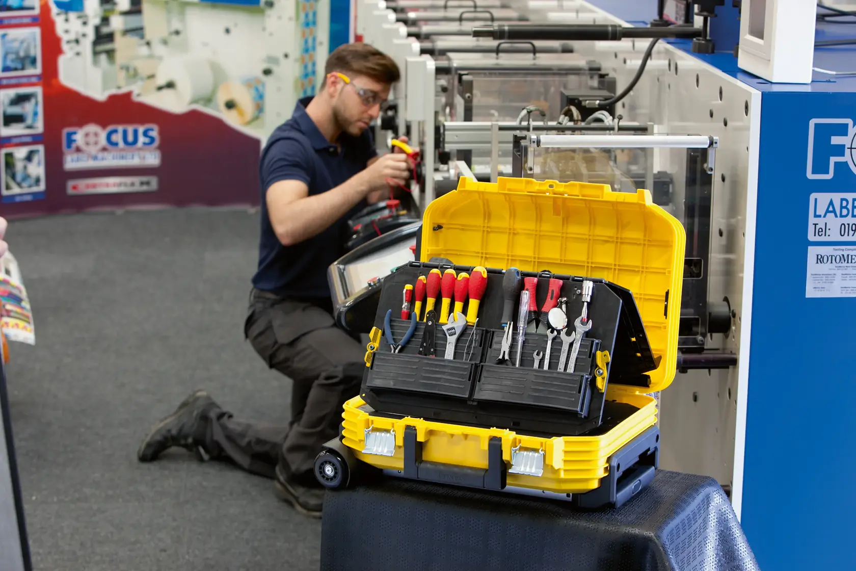 STANLEY FMST1-71943 yellow and black tool box with assorted hand tools, open on a worktable near machinery.