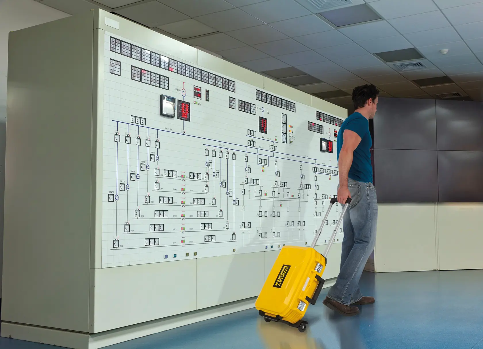 STANLEY FMST1-71943 yellow rolling tool case in use, being pulled by a person in an office or control room.