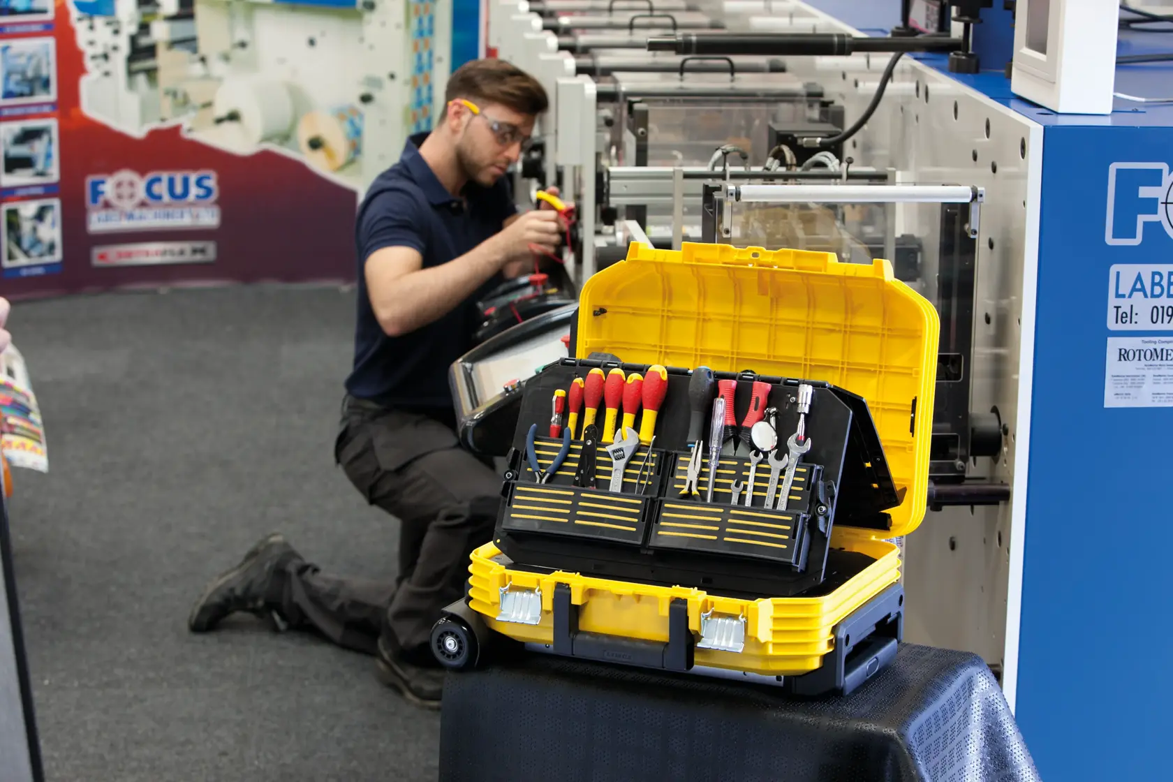 STANLEY FMST1-72383 tool case open, displaying assorted hand tools, yellow and black, in workshop setting.