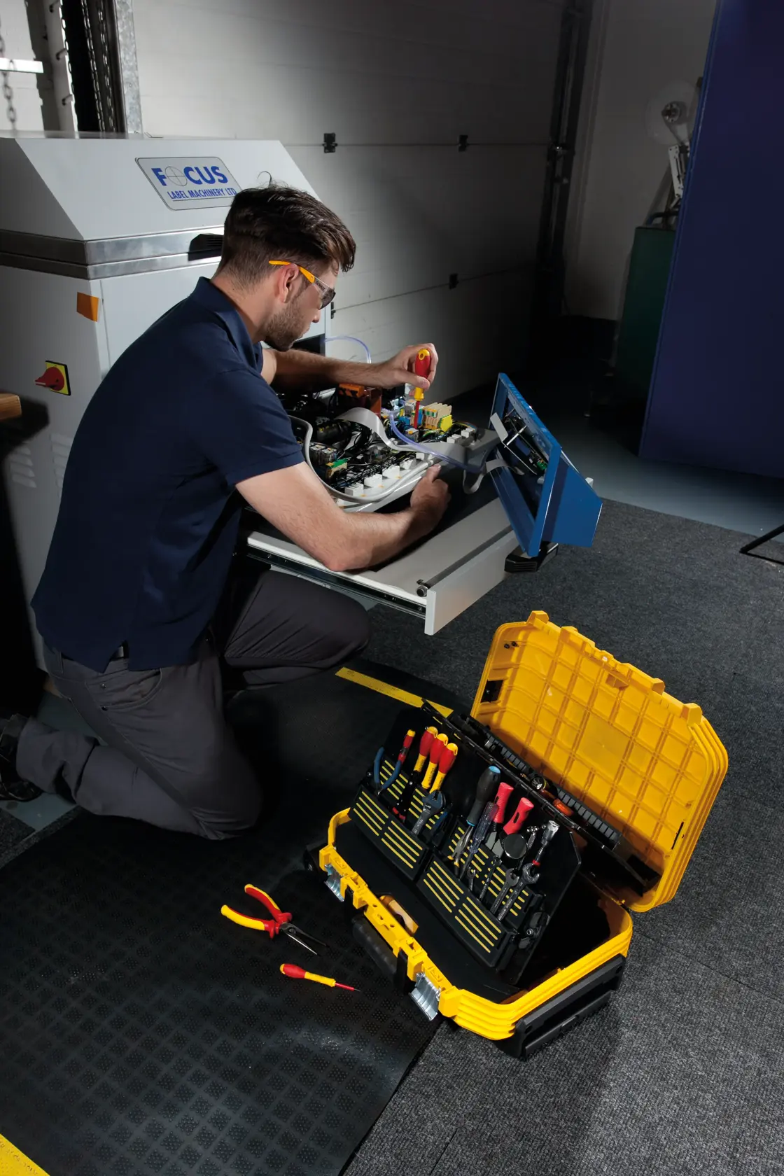 STANLEY FMST1-72383 toolbox with organized hand tools, open on the floor near technician repairing equipment.