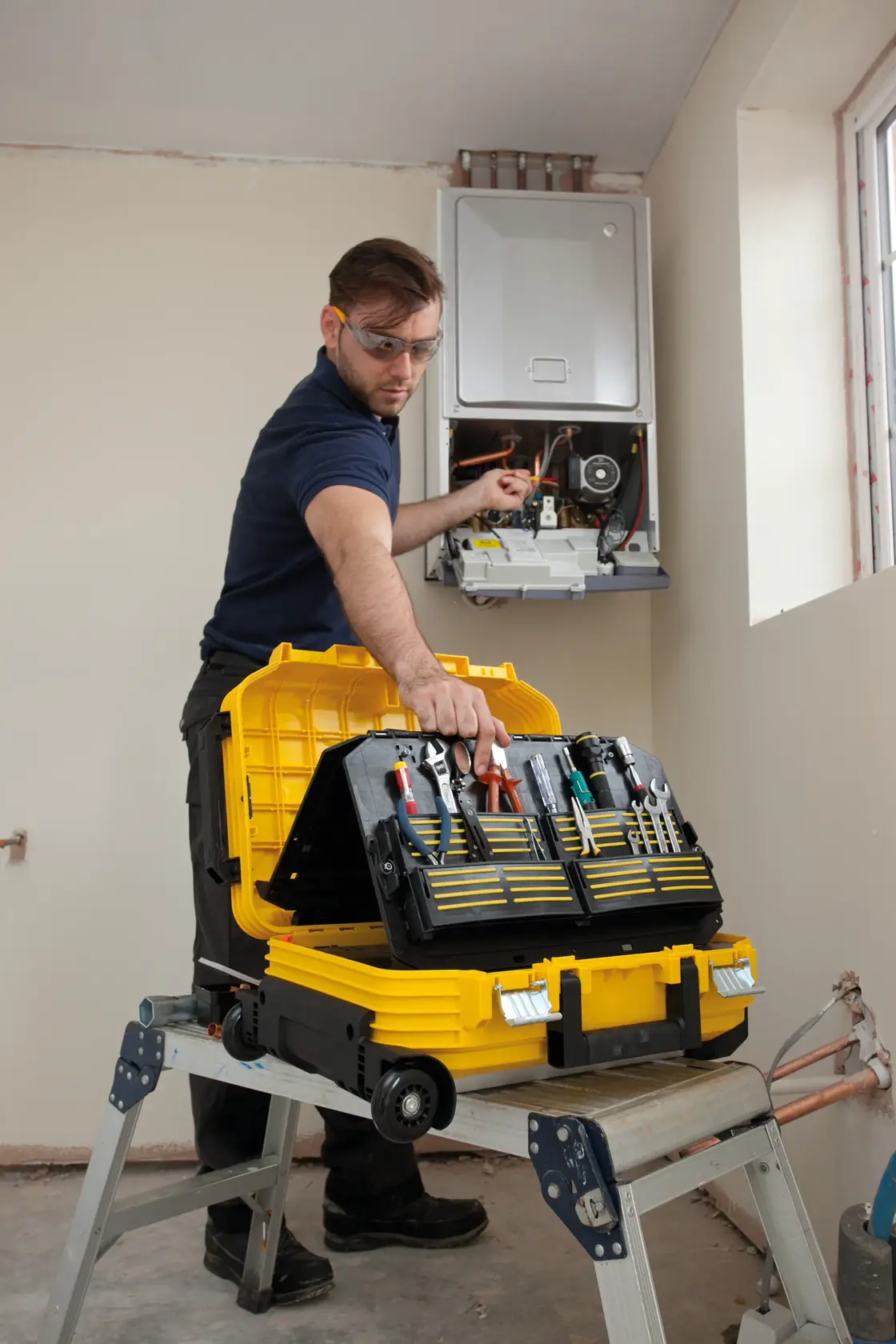 Photo of STANLEY FMST1-72383 tool case open on a step ladder, with technician working on a wall-mounted unit.