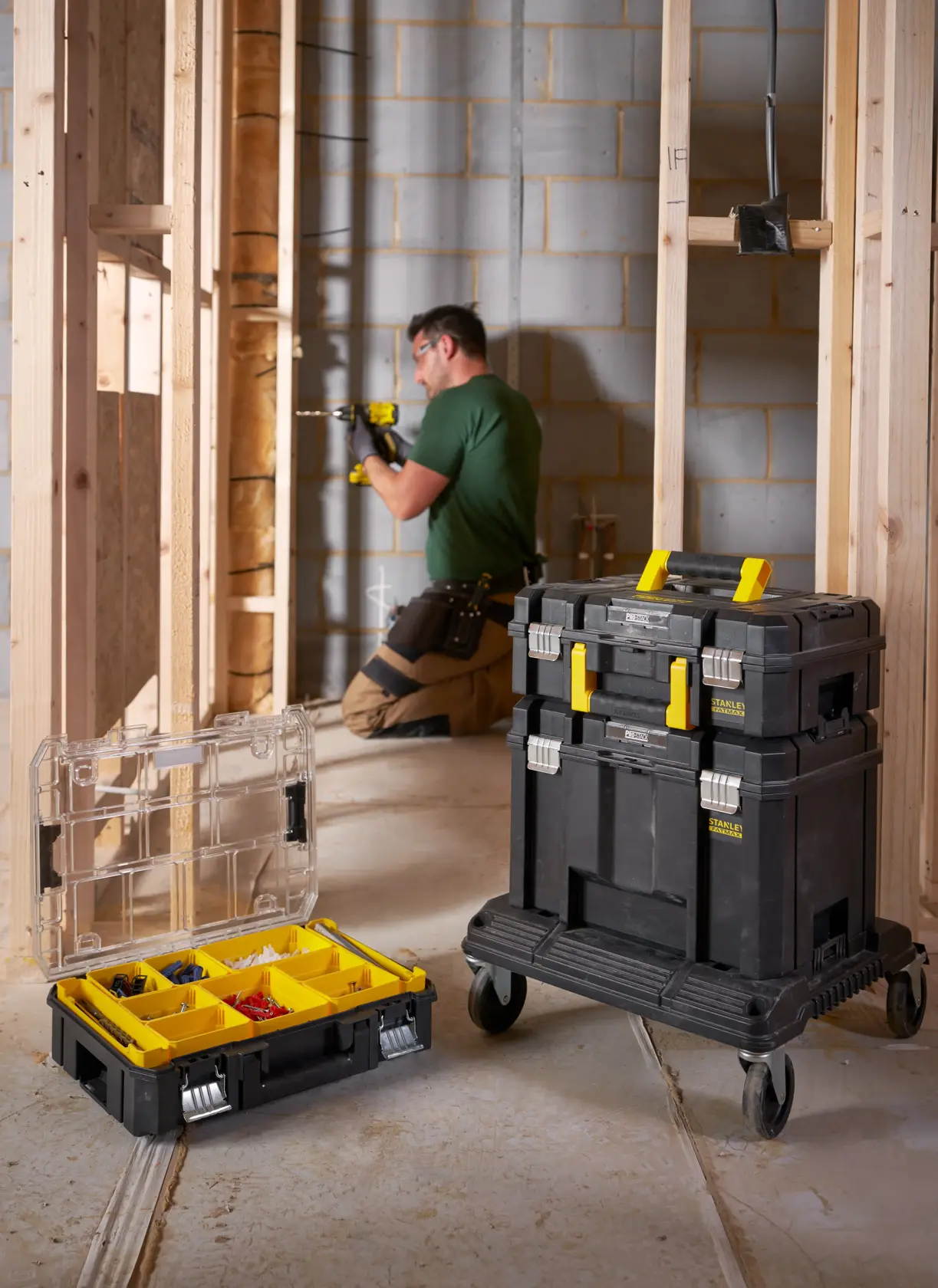 STANLEY FMST1-75502 mobile tool storage stack with yellow handles and organizer box, shown at a construction site.