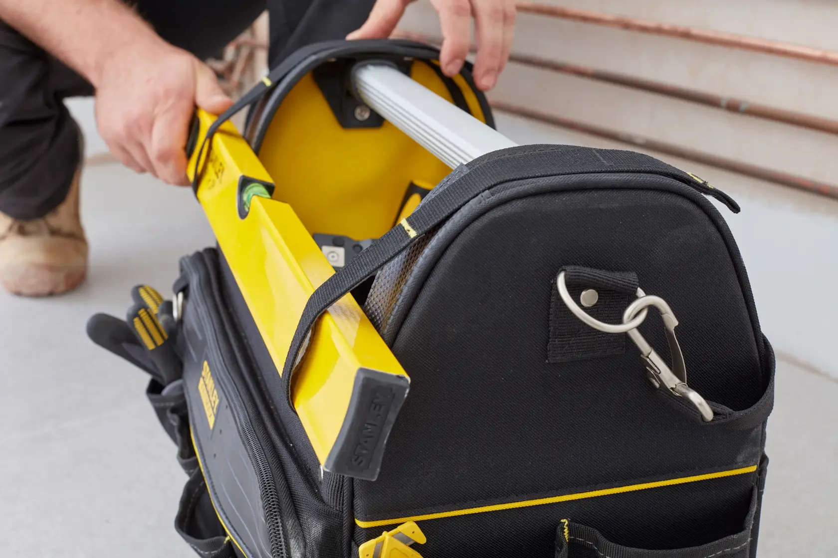 Photo of STANLEY FMST83296-1 tool bag in use, black with yellow trim, holding tools and a yellow level.