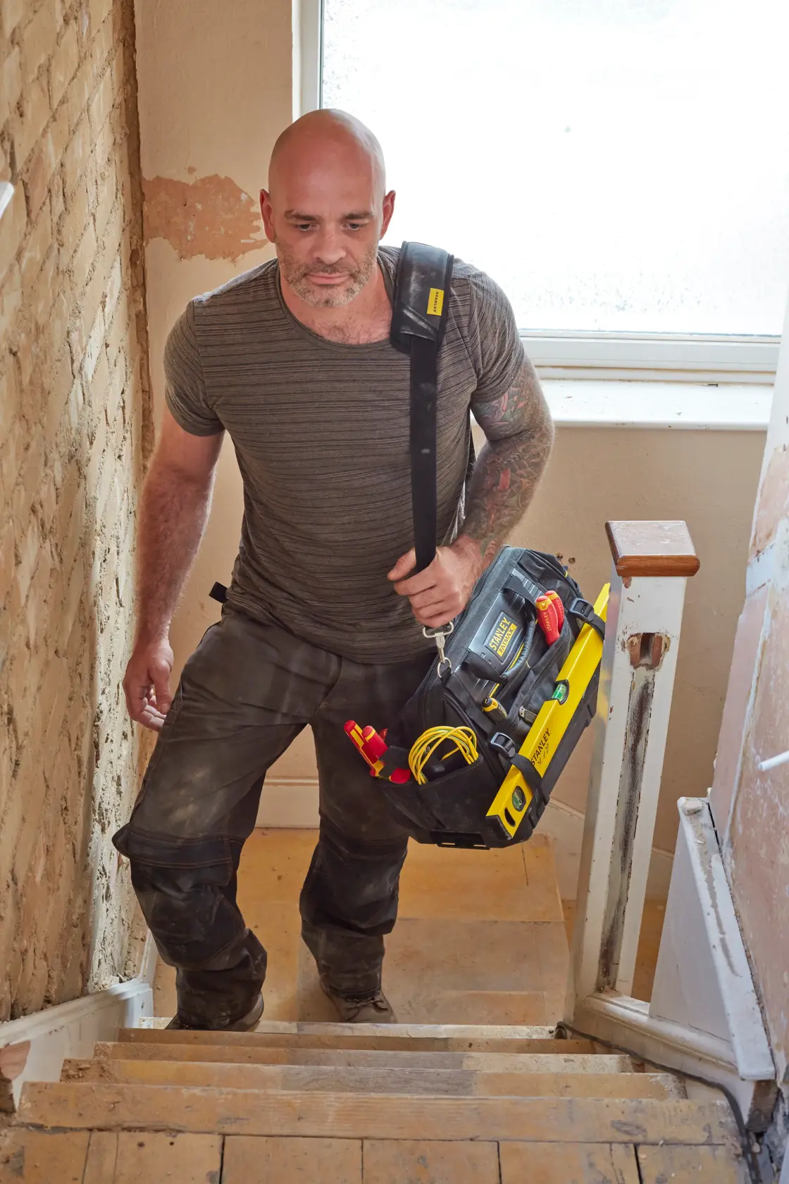 Photo of STANLEY FMST83297-1 tool bag with shoulder strap and tools, carried by person up stairs.