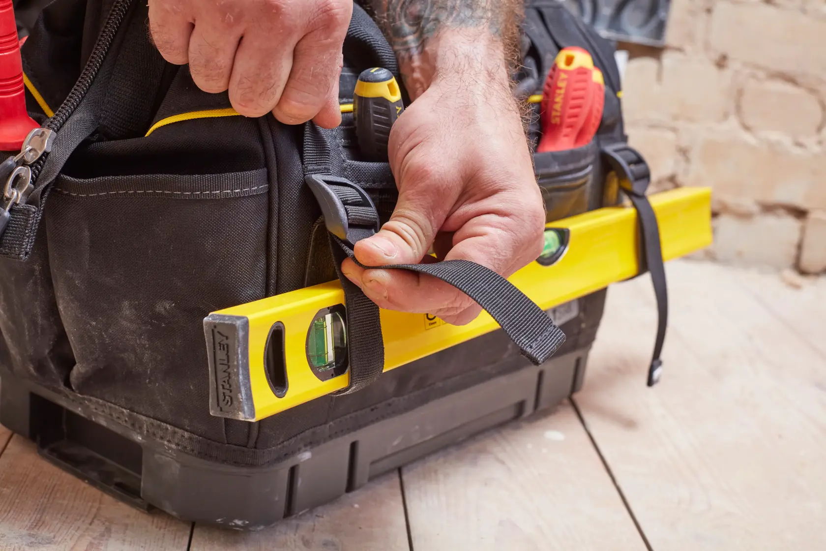 STANLEY FMST83297-1 tool bag held by hand, with yellow level secured on side and tools visible inside.