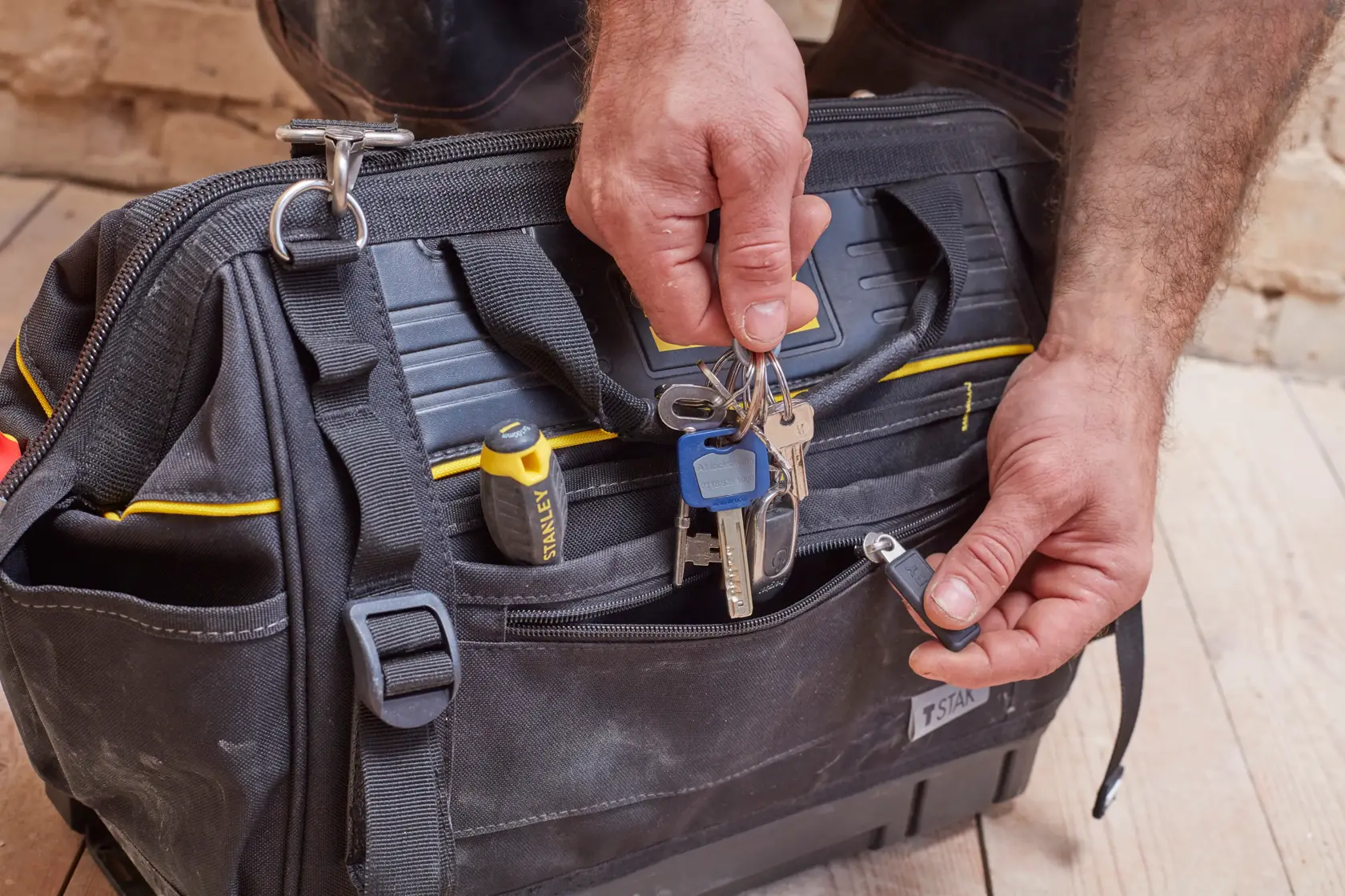 STANLEY FMST83297-1 tool bag, front angle, black with yellow accents, keys and screwdriver in pocket.